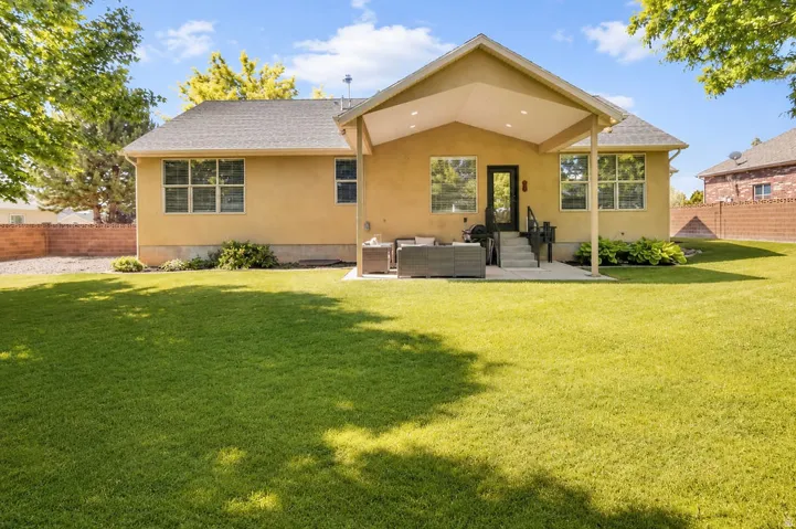 Expansive rear yard featuring a large manicured lawn and mature trees