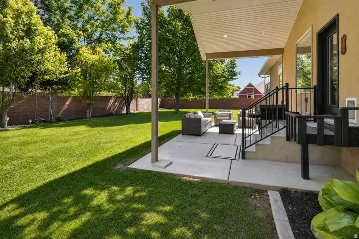 Covered outdoor patio with concrete flooring, accented by a black metal railing and steps leading to a raised entry