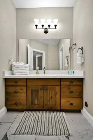 Bathroom featuring a wood-finish vanity with ample storage, a white countertop, and an integrated sink