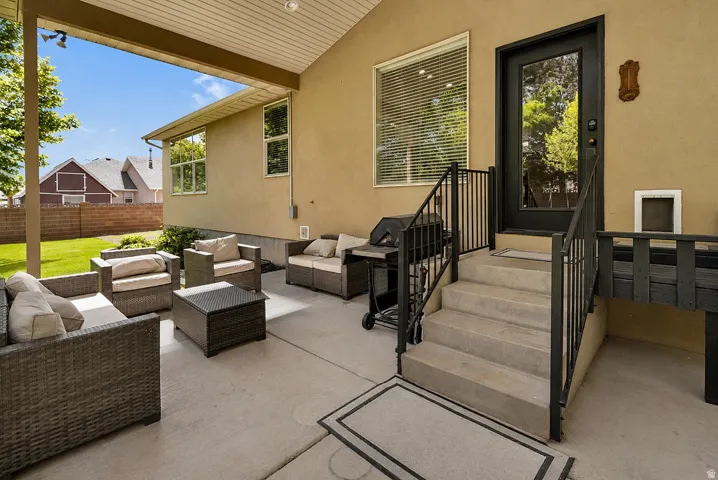 Expansive covered patio with concrete flooring, stucco exterior, and black framed door