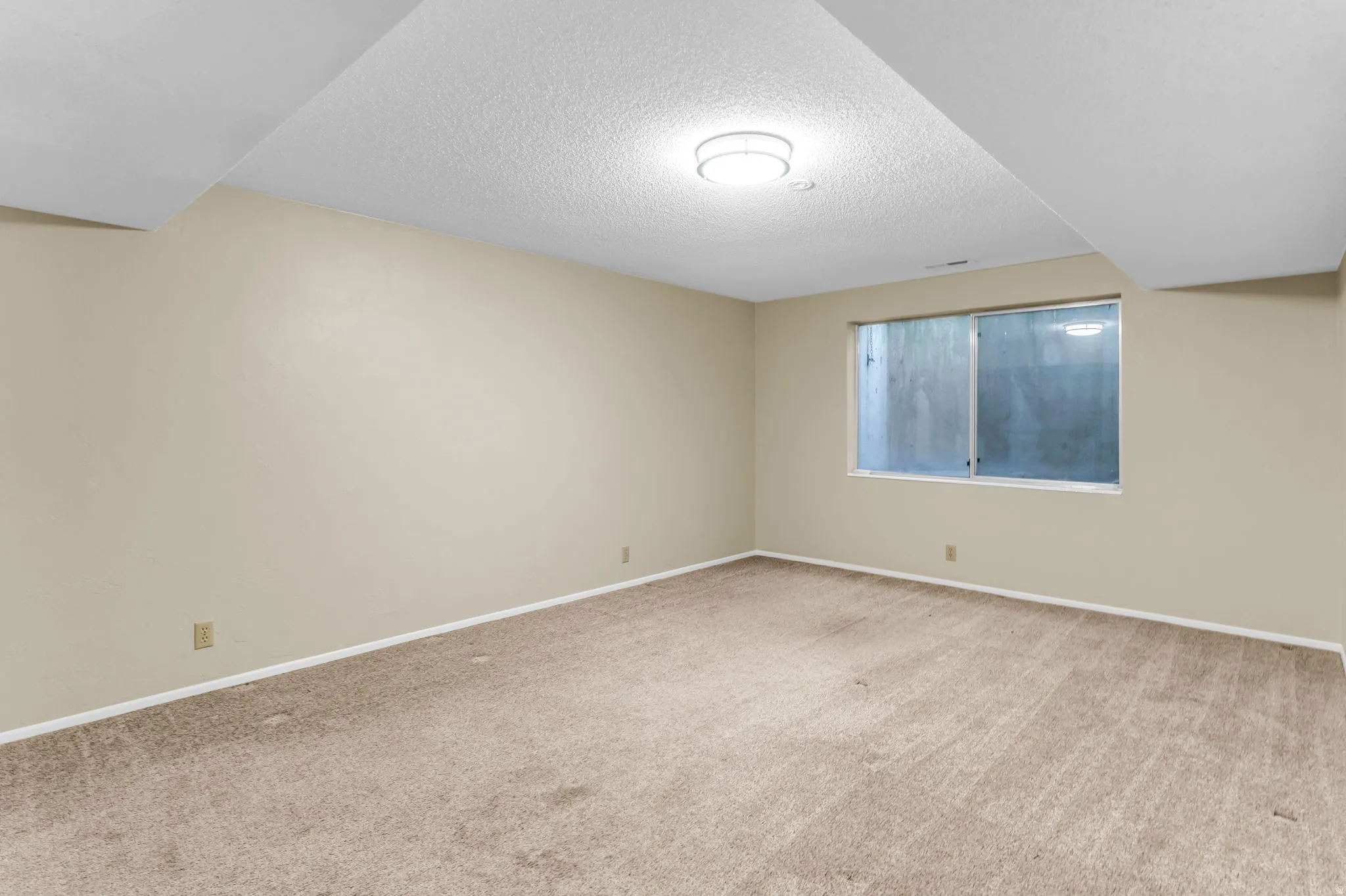 Carpeted room featuring a window and overhead lighting
