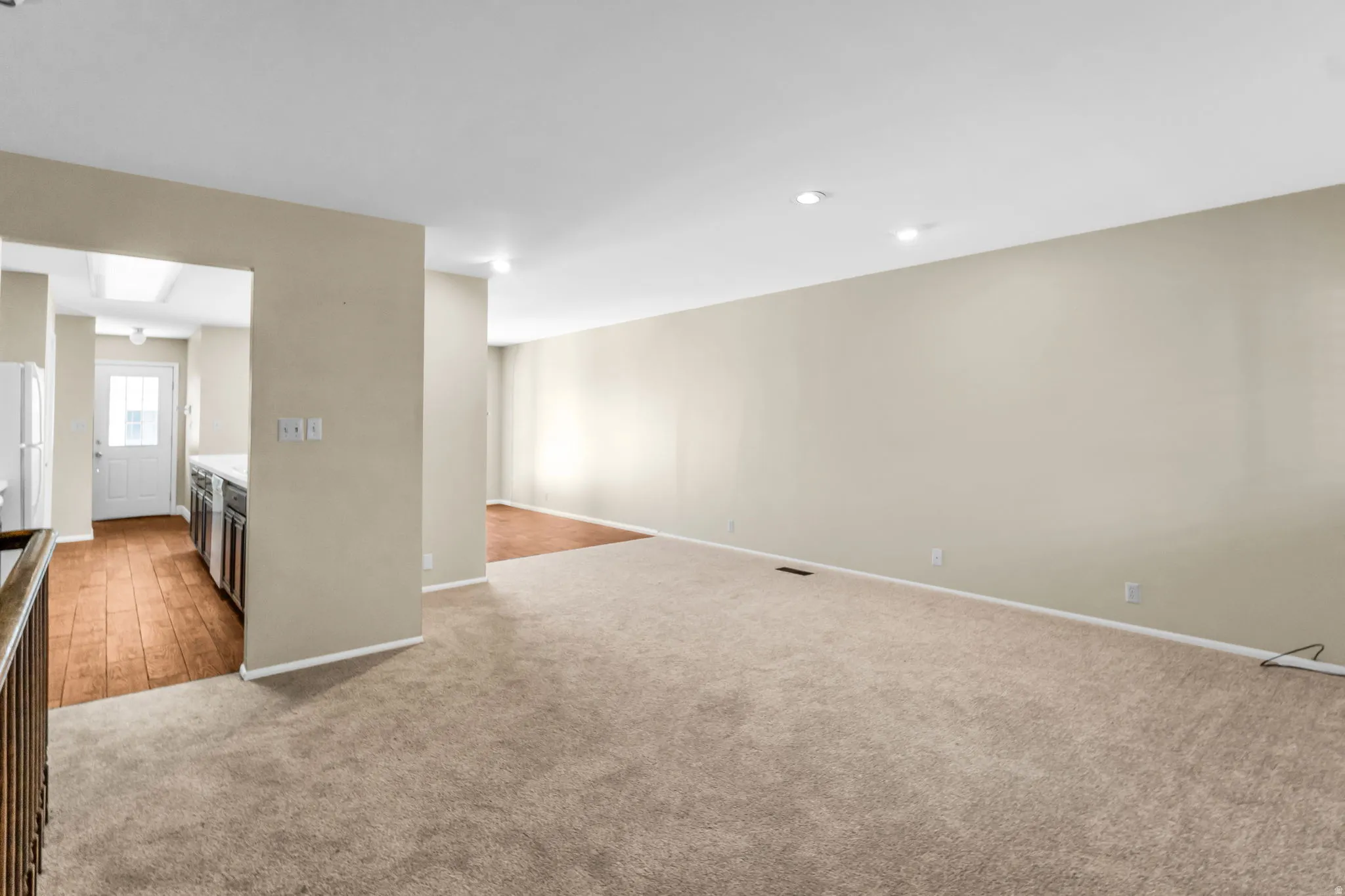 Open-concept living area with neutral carpeting and recessed lighting