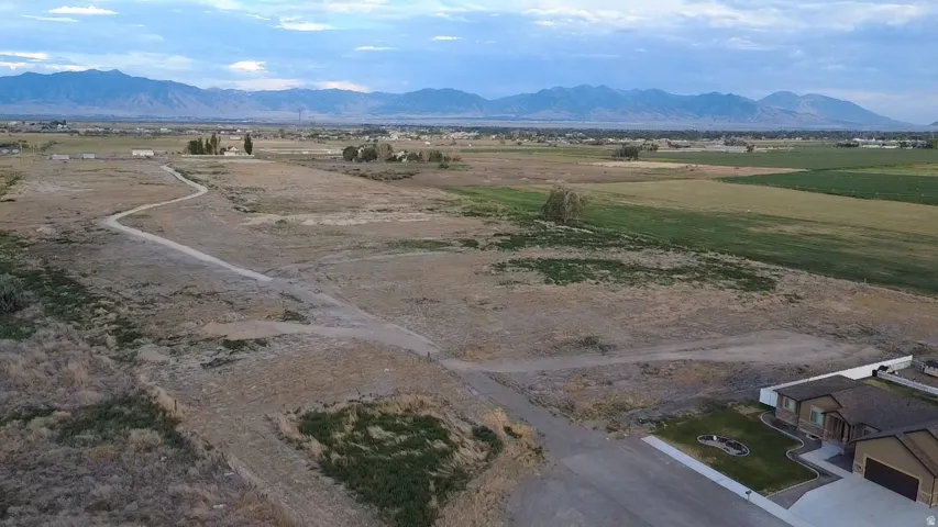 Expansive undeveloped land featuring a winding dirt path, diverse vegetation, and distant mountain ranges