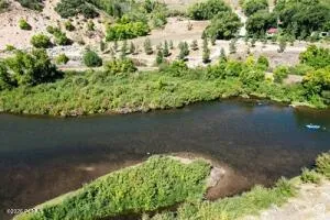 River frontage with natural surroundings featuring a sandy bank, mature trees, and diverse vegetation