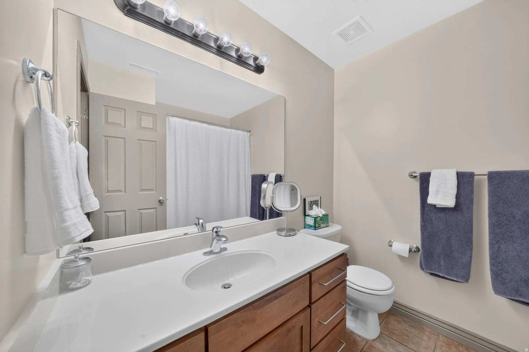 Bathroom vanity featuring a white countertop with an integrated sink, chrome faucet, and wood-finish cabinetry