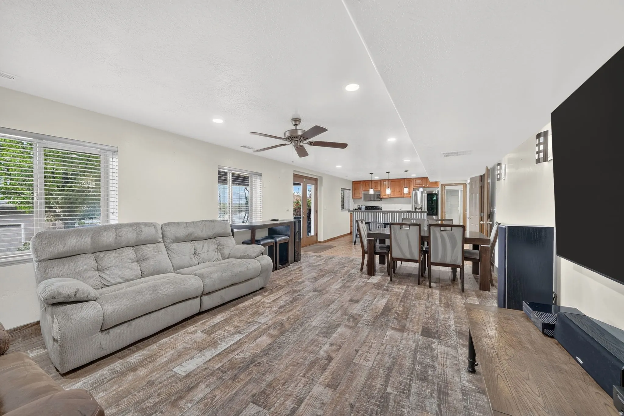 Open-concept living space featuring wood-finish flooring, recessed lighting, and a ceiling fan
