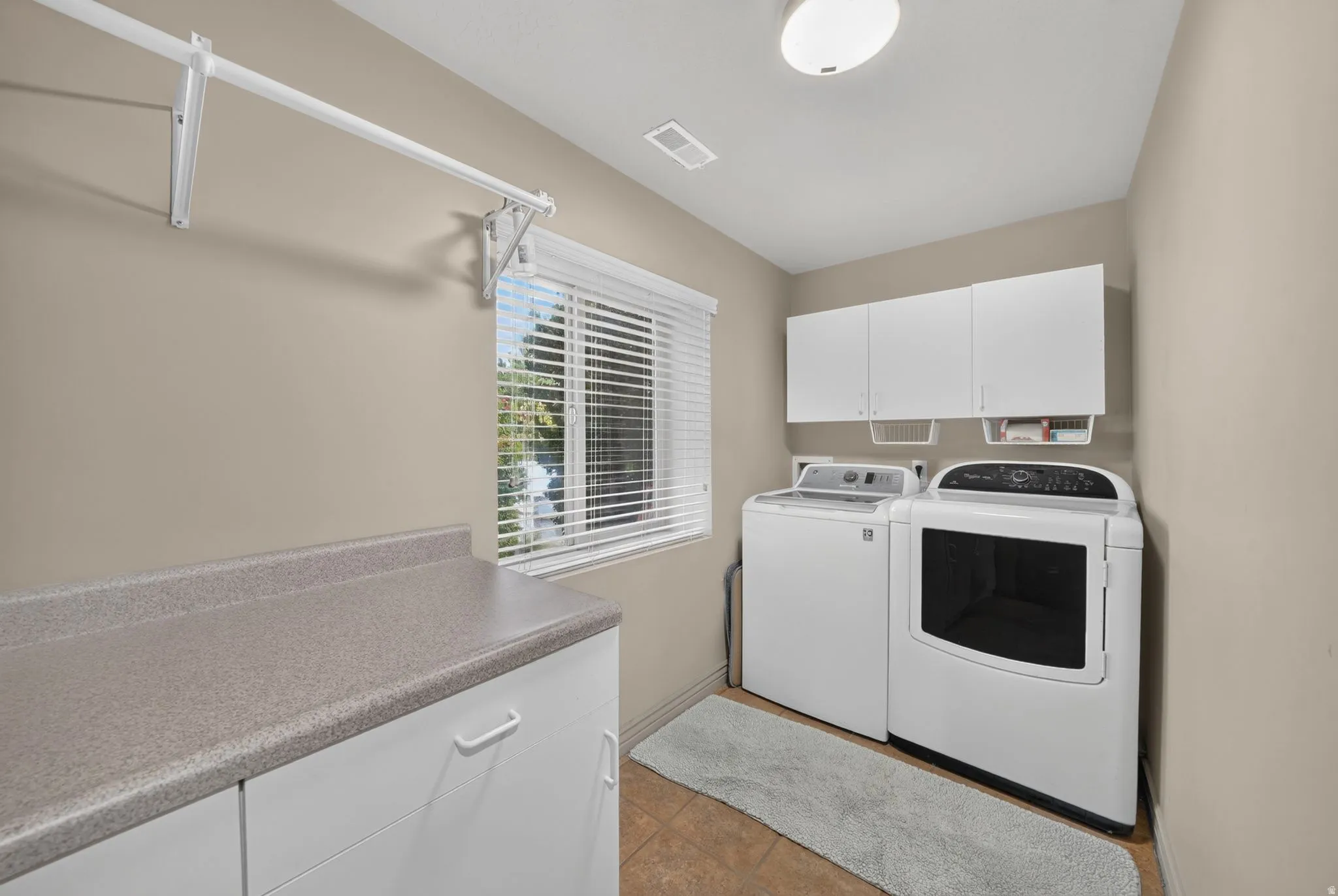 Laundry room with built-in cabinetry, durable countertop space, and a ceiling-mounted light fixture
