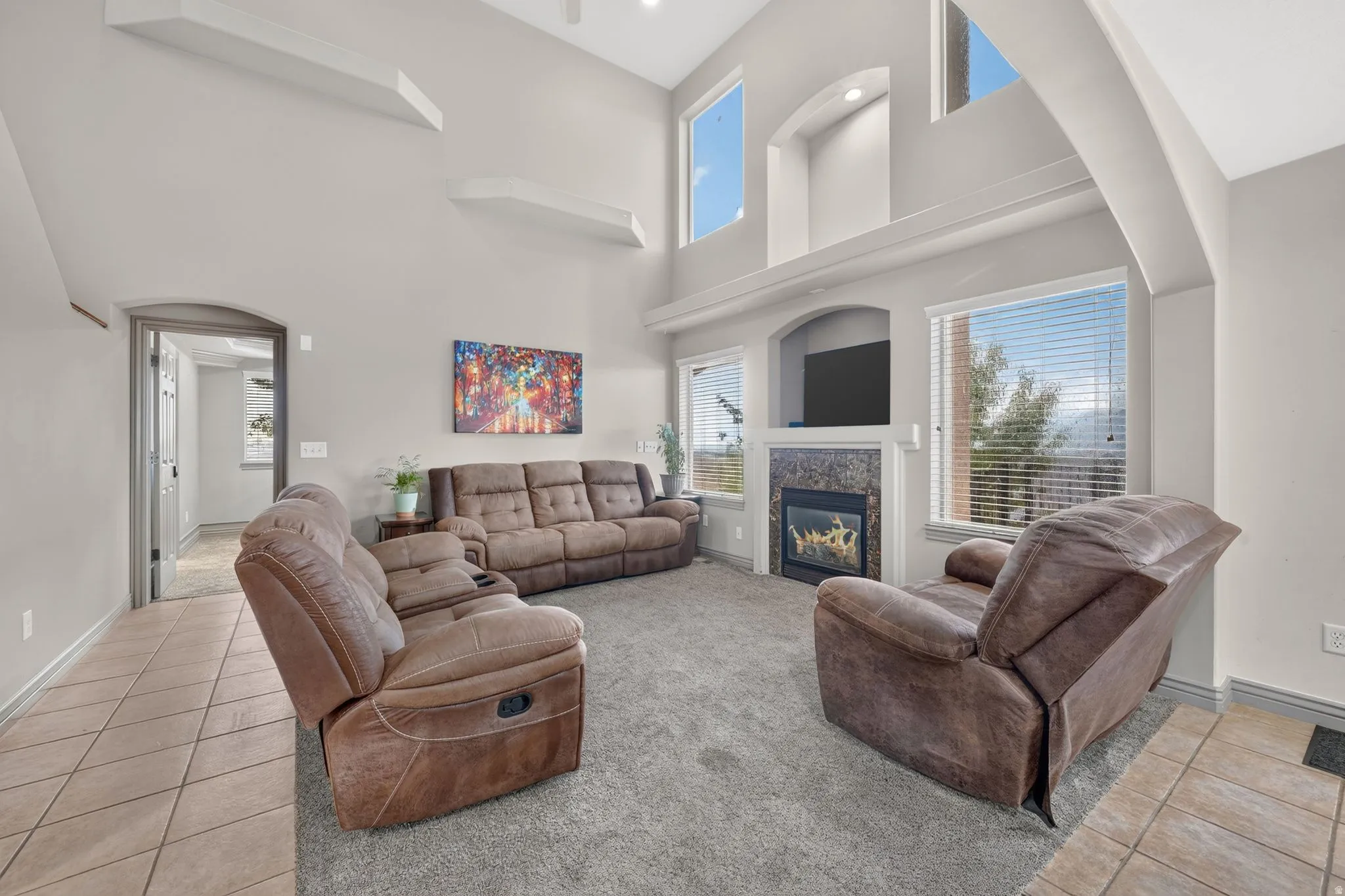 Vaulted ceilings define this living area, featuring a built-in fireplace with a stone surround, a dedicated television alcove, and multiple windows
