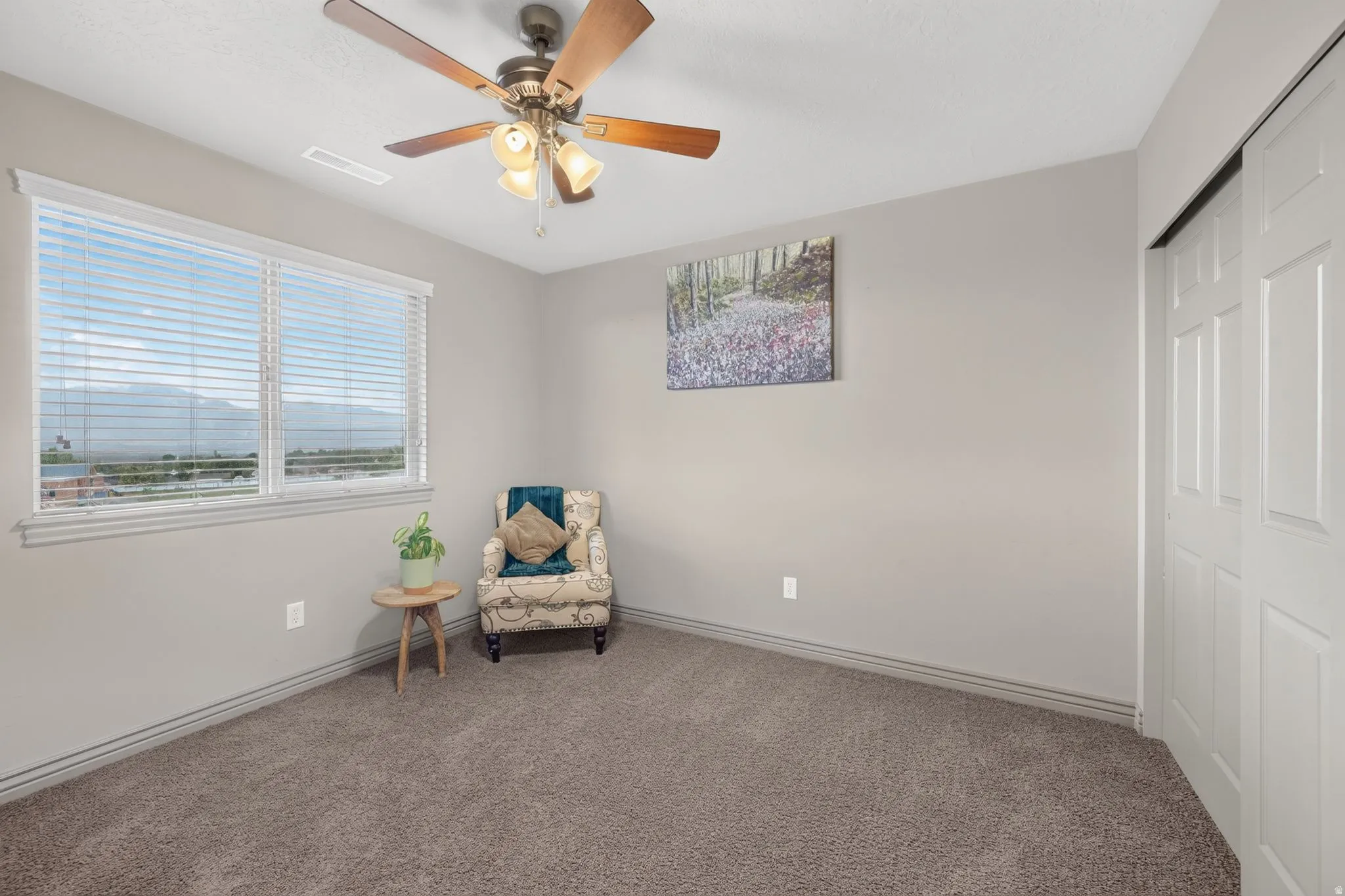 Bedroom featuring a dual-pane window with horizontal blinds, a ceiling fan with integrated lighting, neutral wall paint, and plush carpeting