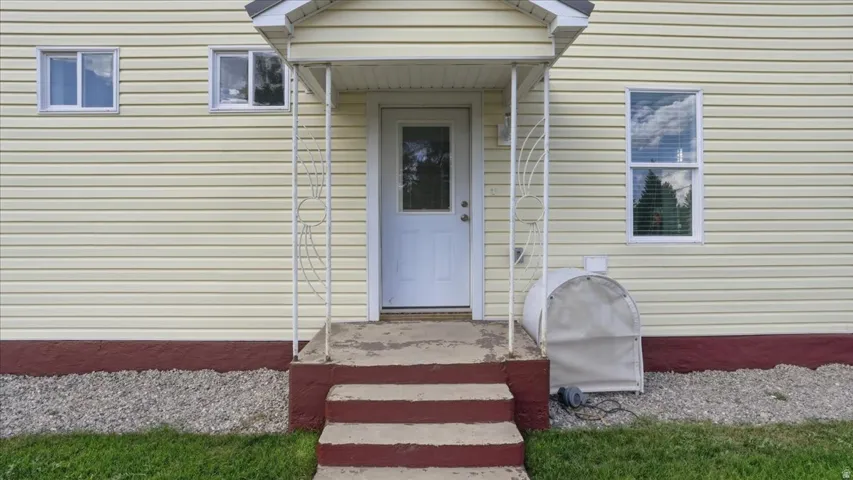 Entryway featuring a white door with glass insert, concrete steps, and wrought iron railing