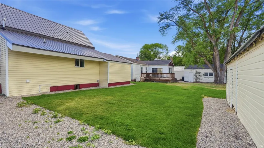 Expansive backyard featuring a manicured lawn, established landscaping, gravel pathways, and a detached structure