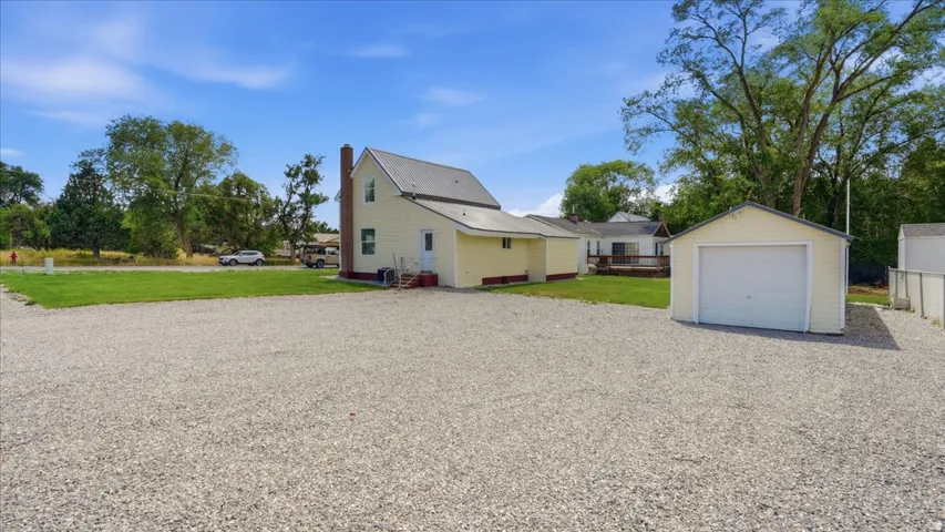 Expansive gravel driveway with a detached single-car garage featuring a white overhead door