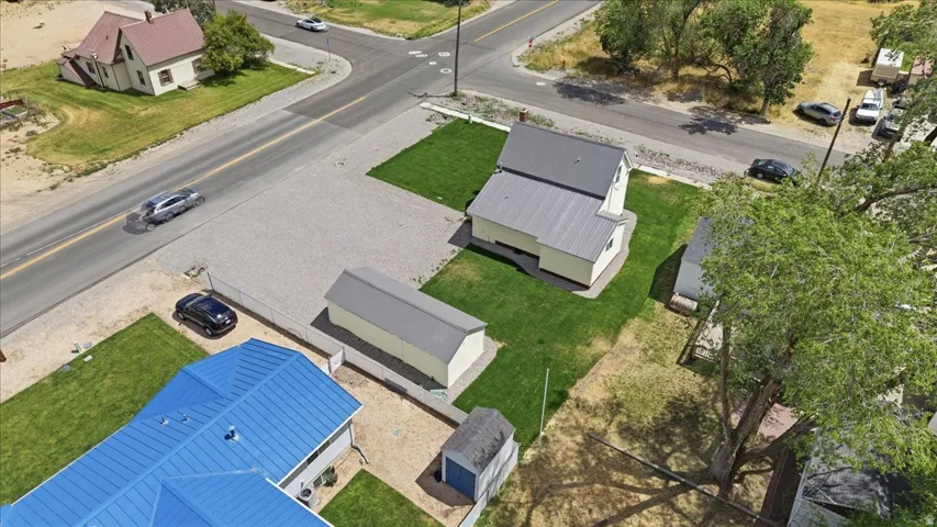 Property featuring a primary building with a metal roof, a secondary structure with a metal roof, a gravel parking area, and manicured green spaces
