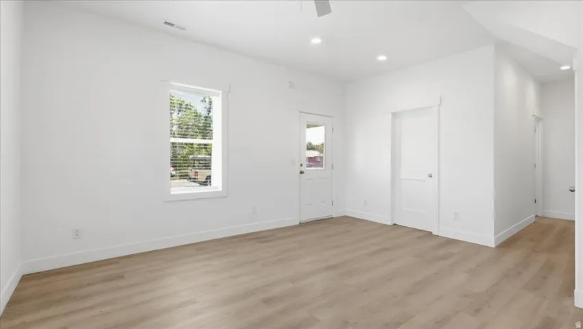 Spacious room featuring wood-finish flooring, recessed lighting, and a neutral white color palette