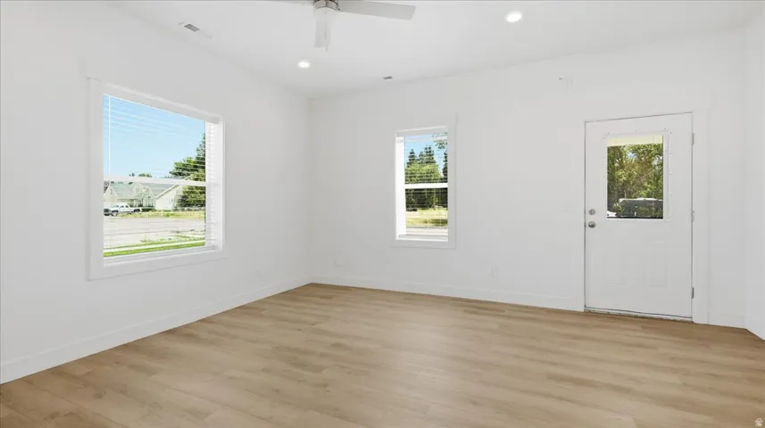 Open concept living area featuring wood-finish flooring, two large windows with blinds, a ceiling fan, and recessed lighting