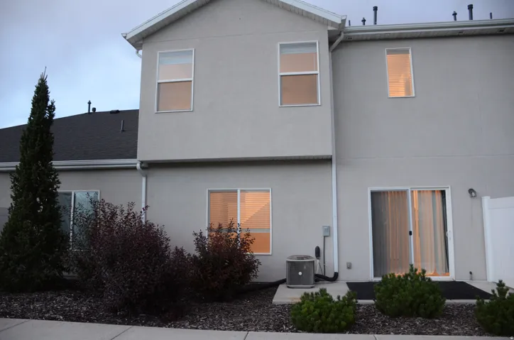 Rear exterior featuring stucco siding, multiple windows, and a sliding glass door