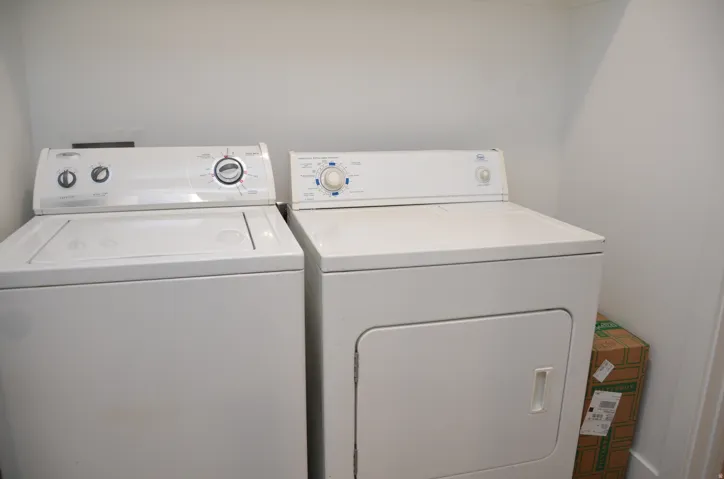 Dedicated laundry space featuring a white top-load washing machine and a white front-load dryer