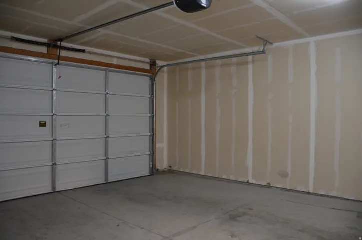 Garage interior featuring a sectional overhead door, concrete flooring, and unfinished drywall walls