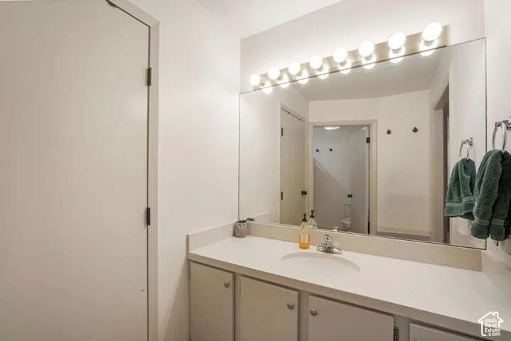 Bathroom vanity featuring an integrated sink, polished chrome faucet, and expansive wall-mounted mirror