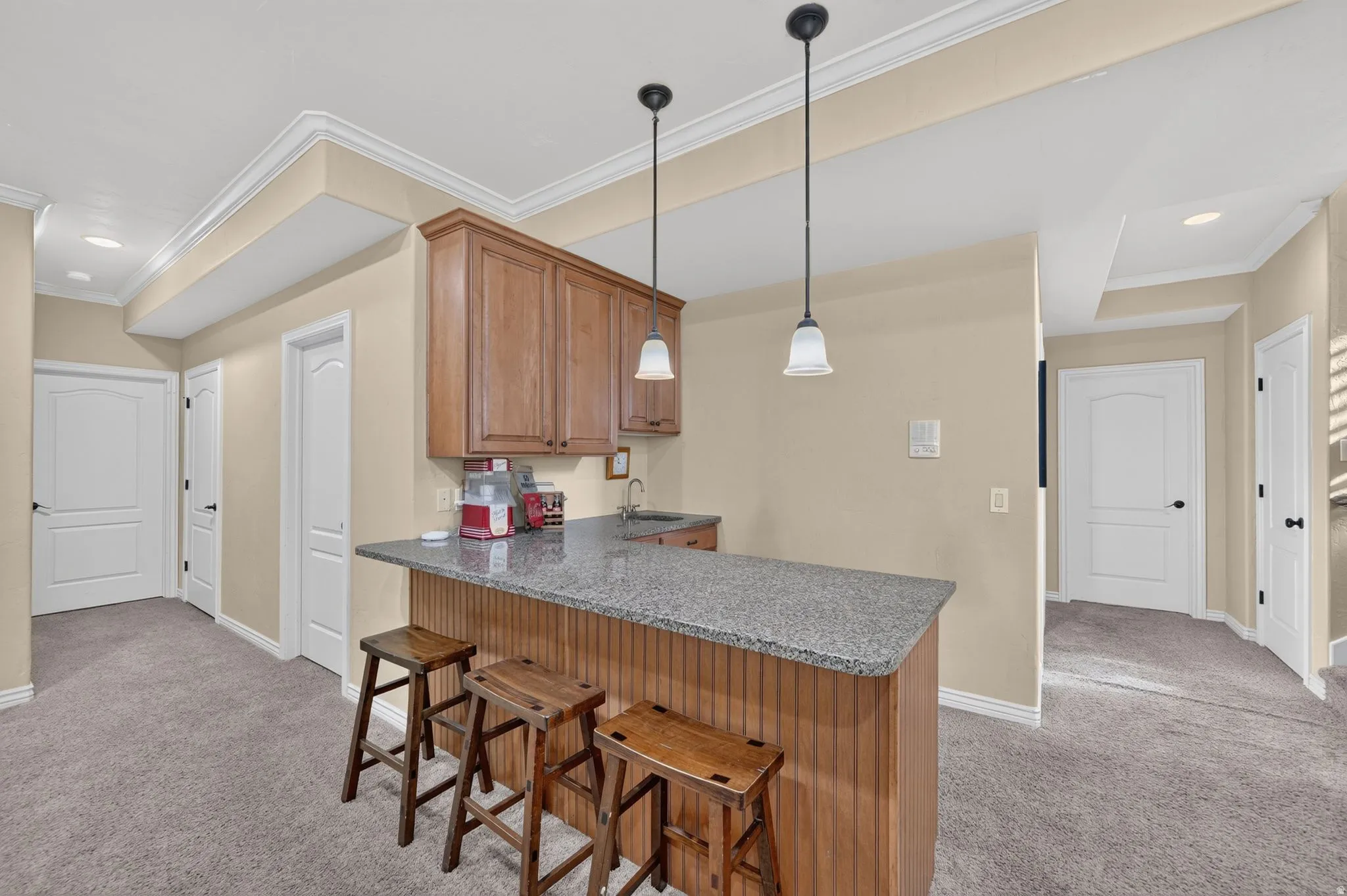 Downstairs kitchenette with barstools, cabinets, and countertops