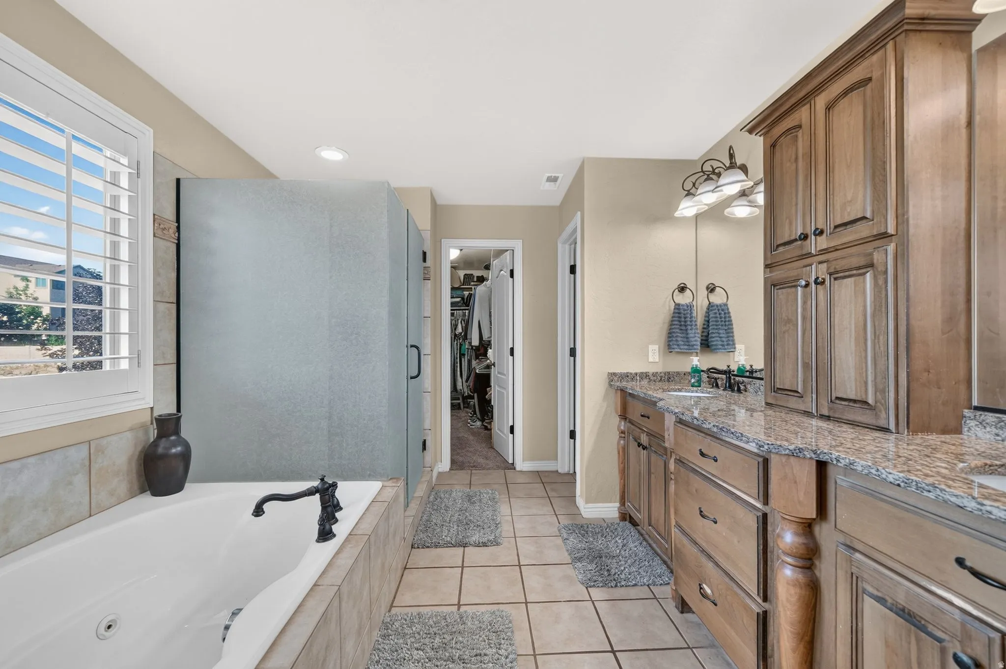 Primary bathroom with large tub, walk in shower, double vanity, and walk in closet