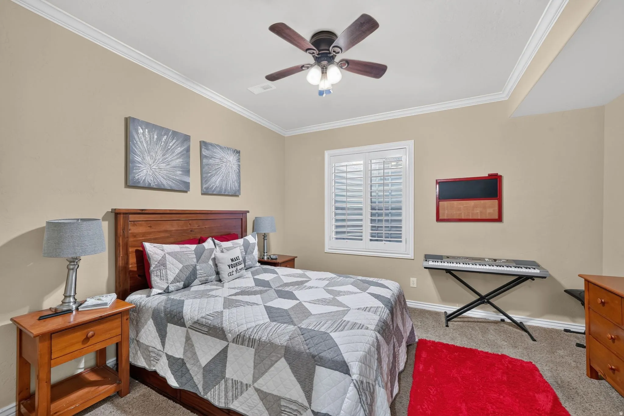 Second downstairs bedroom featuring carpet, a ceiling fan, crown molding, and a window with white plantation shutters