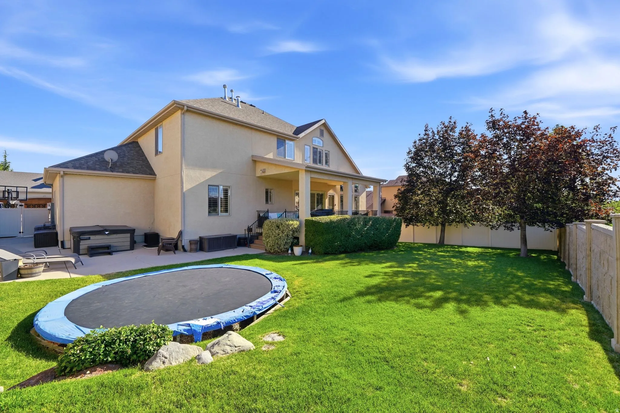 Views of the back of the house showing large yard, mature trees, and covered patio deck