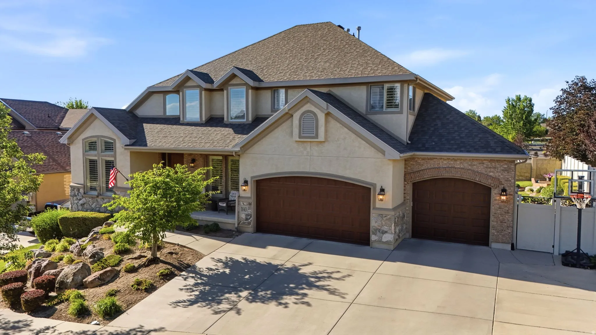 Front house exterior showcasing 3 car garage, mature trees, basketball hoop, and RV parking