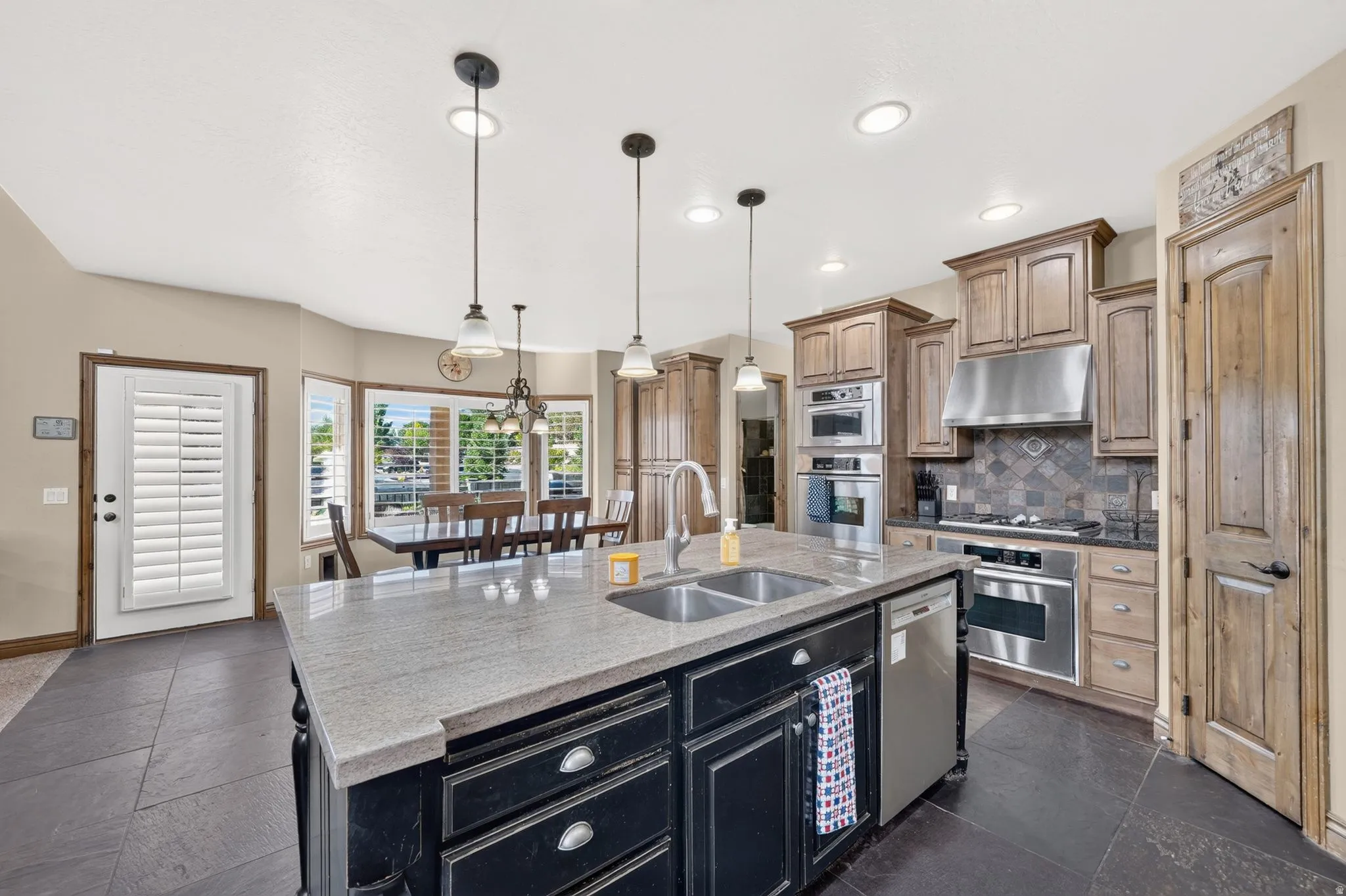 Spacious kitchen featuring a large island with dual sinks, stone countertops, and dark cabinetry