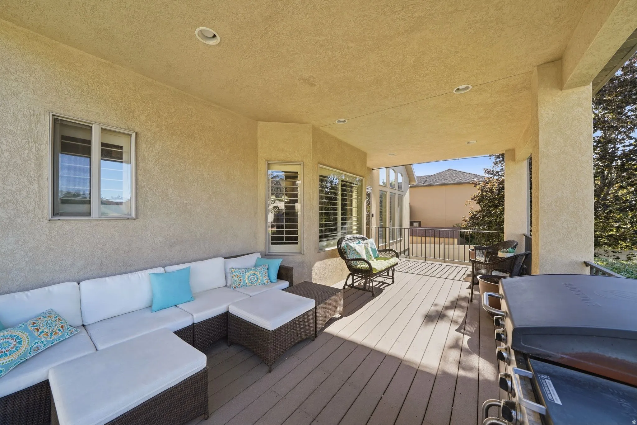 Covered and shaded patio with furniture, Blackstone grill, and backyard views