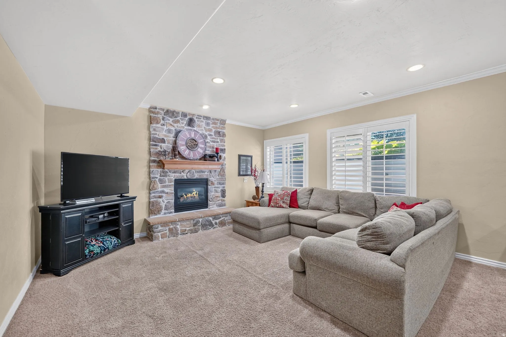 Basement living room featuring lots of natural light, large windows, and stoned fireplace