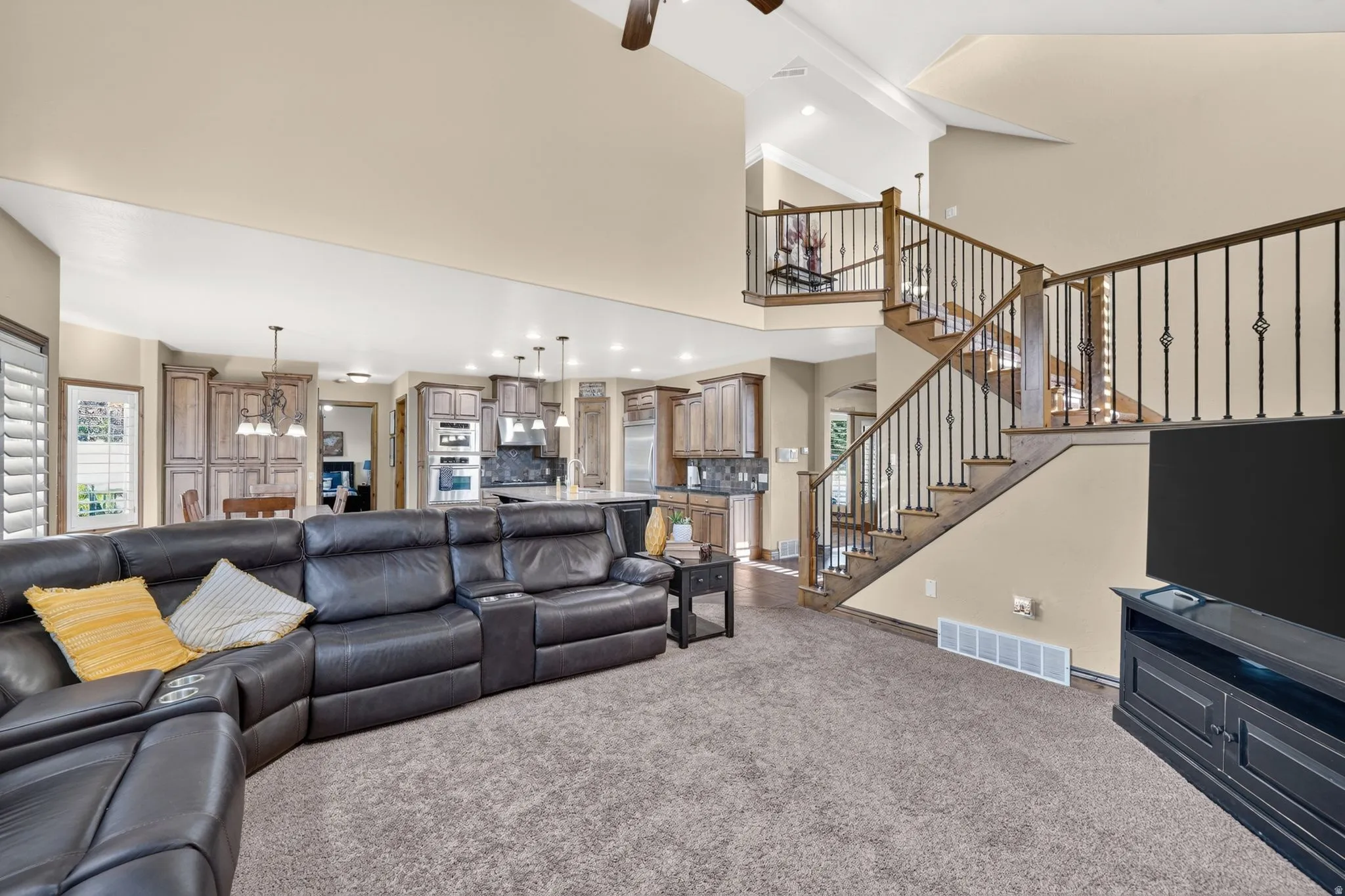 Large living room with ample seating, and views of the large staircase going upstairs