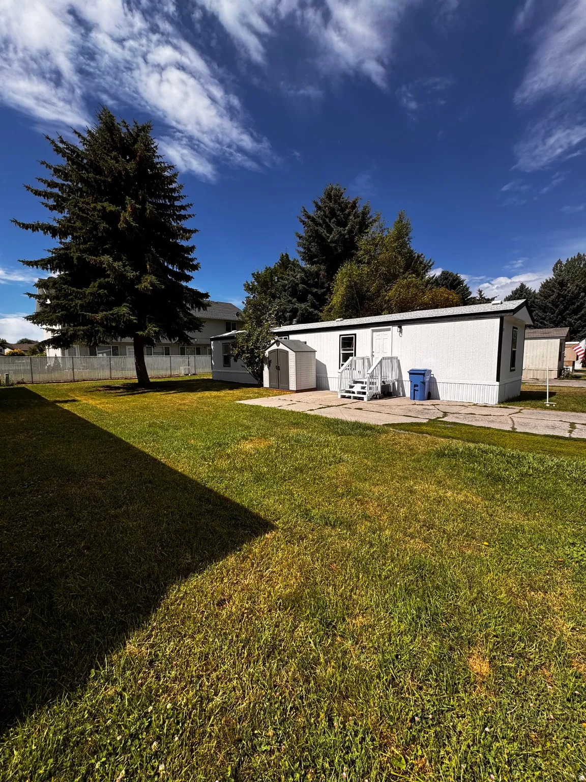 White-sided structure with a metal roof and an outdoor storage shed