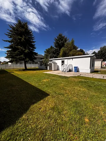 White-sided structure with a metal roof and an outdoor storage shed