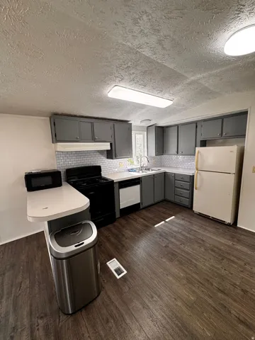 Kitchen featuring wood-finish flooring, gray cabinetry, white subway tile backsplash, and white countertops