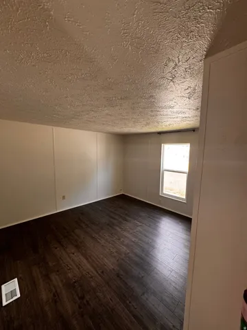 Room featuring wood-finish flooring, light-toned walls, and a window providing natural light