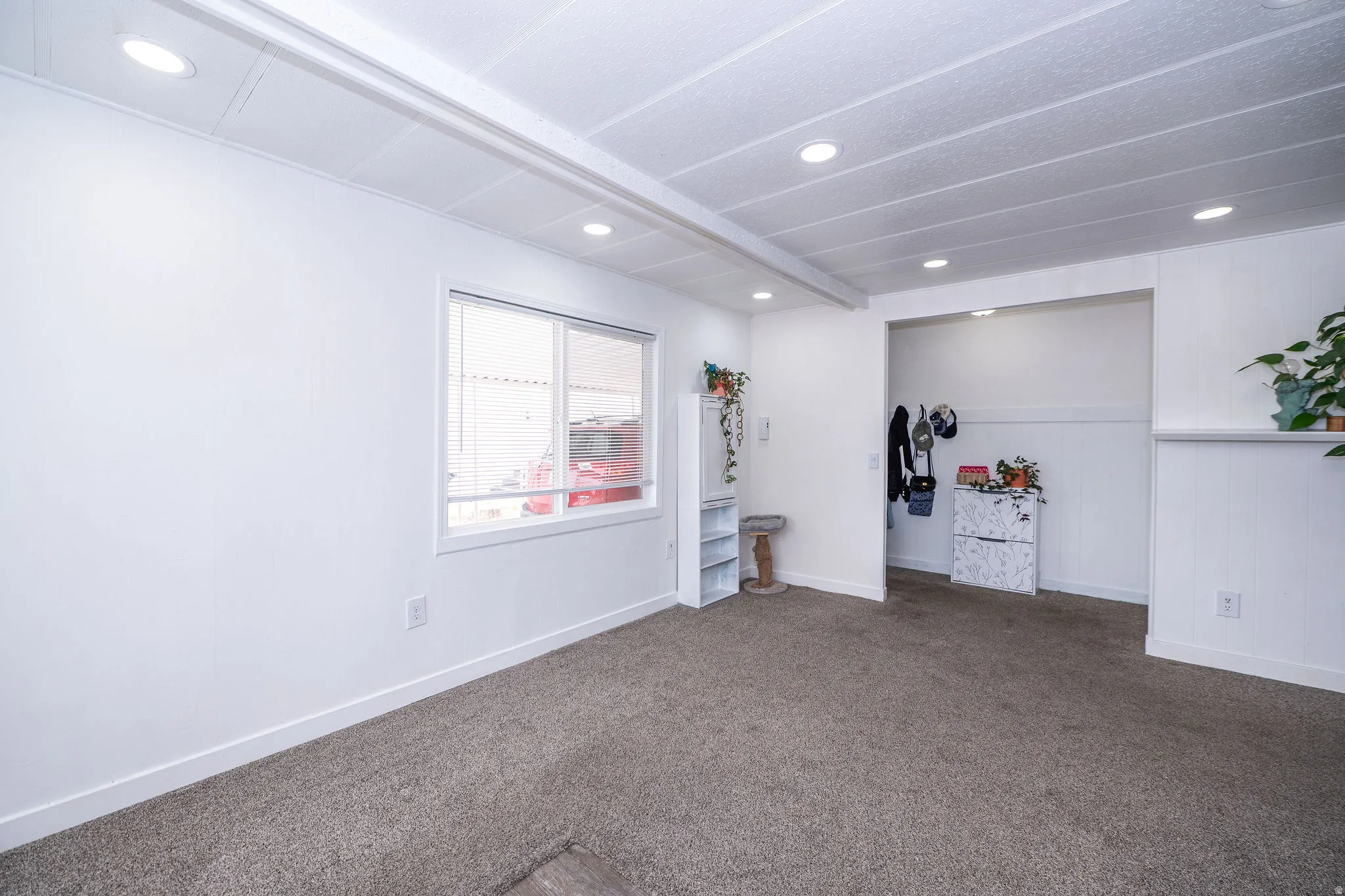 Bright interior space featuring recessed lighting, a window with white trim, and neutral carpeting