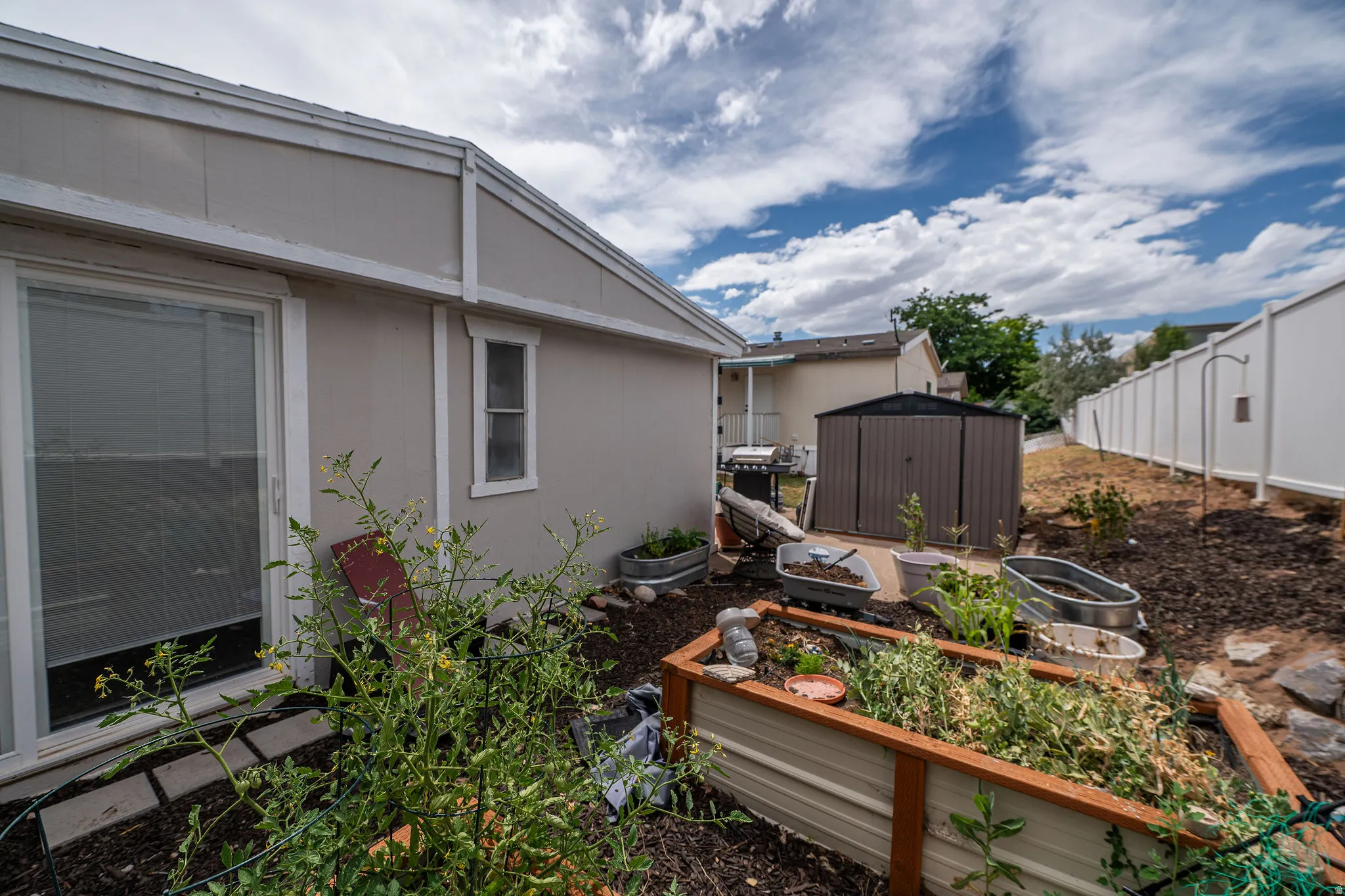 Expansive backyard featuring a privacy fence, built-in planters, and an outdoor storage shed