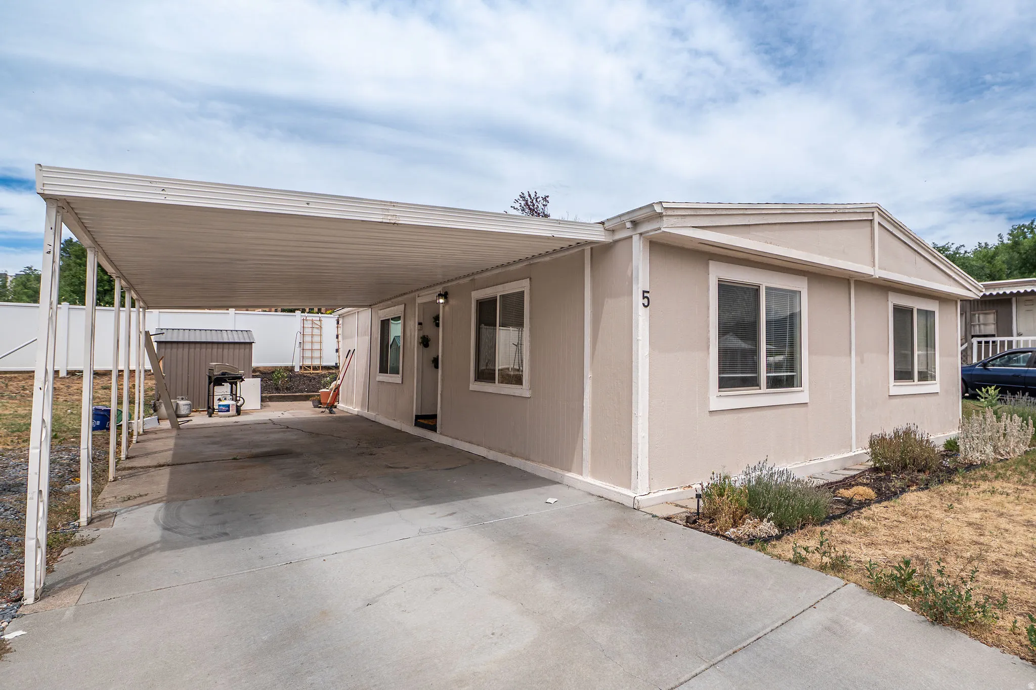 Exterior featuring a covered carport, light-colored siding, and multiple windows