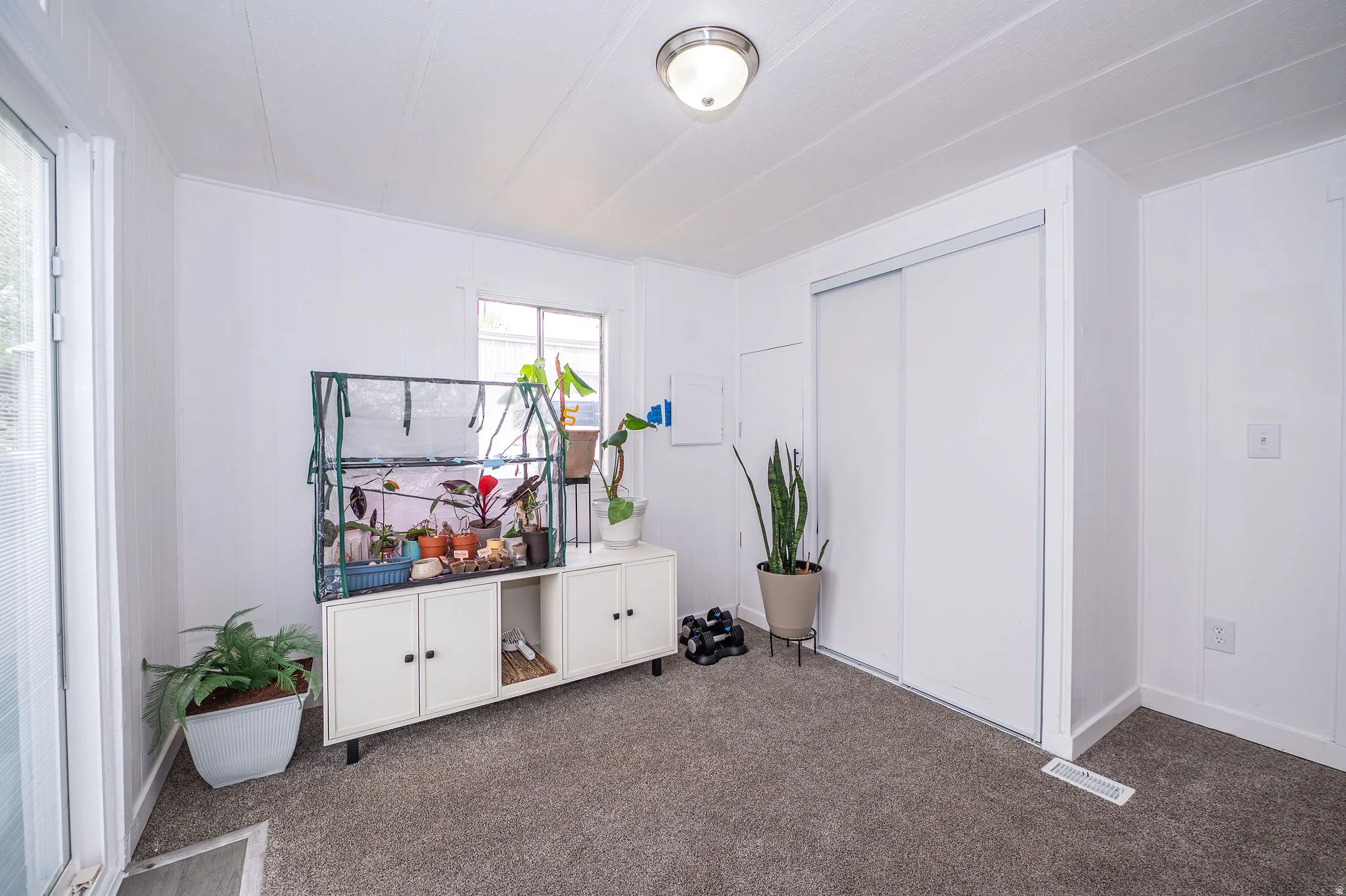 Neutral white walls with textured paneling, gray carpet flooring, and a large sliding door closet