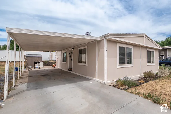Exterior featuring a covered carport, light-colored siding, and multiple windows