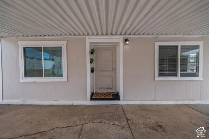 Covered entryway with corrugated metal ceiling, flanked by two sliding windows with white trim