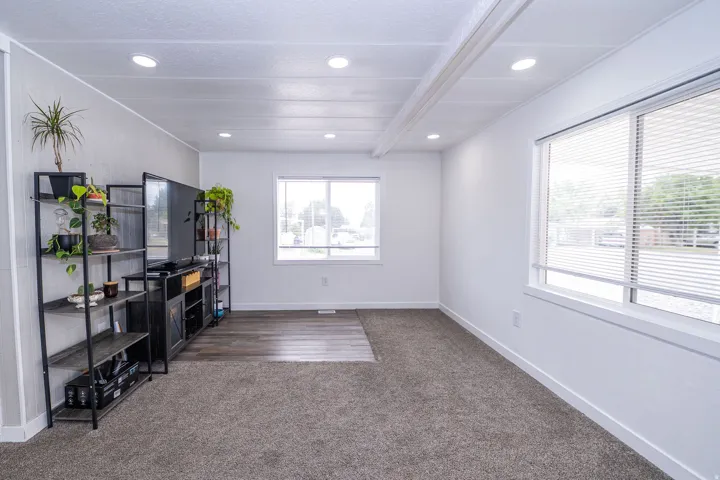 Spacious room featuring recessed lighting, a combination of carpet and wood-finish flooring, and multiple windows with horizontal blinds