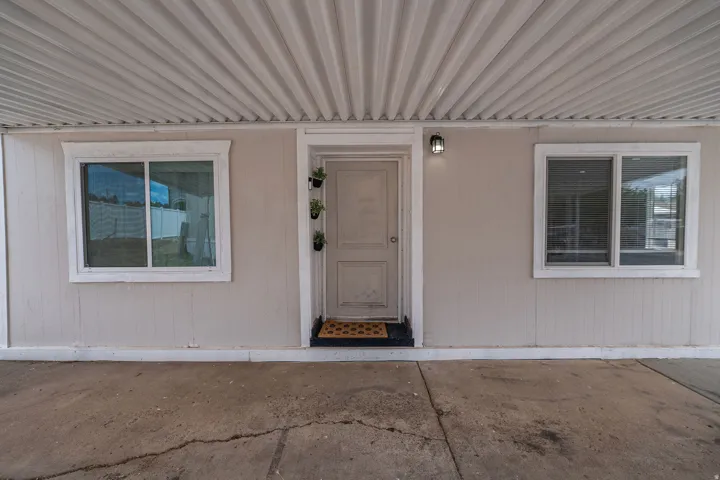 Covered entryway with corrugated metal ceiling, flanked by two sliding windows with white trim