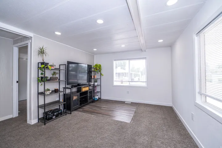 Bright interior space featuring recessed lighting, a combination of carpet and wood-finish flooring, and multiple windows with blinds