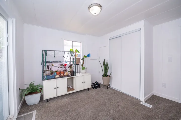 Neutral white walls with textured paneling, gray carpet flooring, and a large sliding door closet