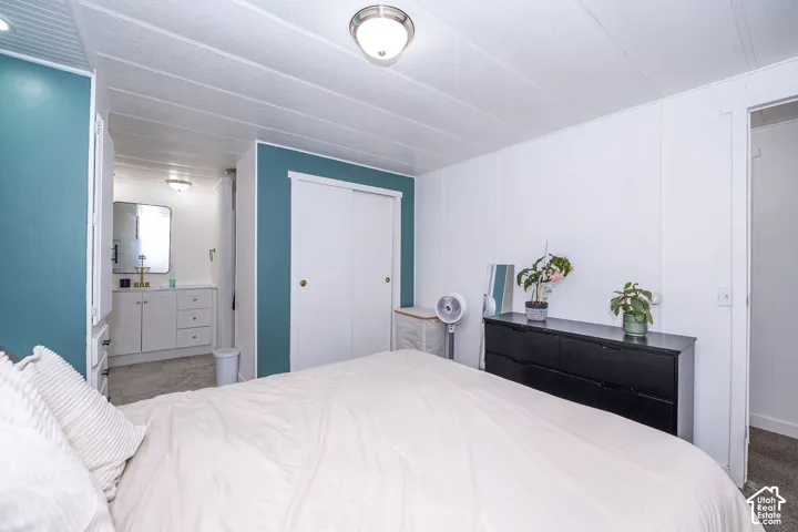 Bedroom featuring a full-height accent wall, white paneled walls, and a recessed sliding closet
