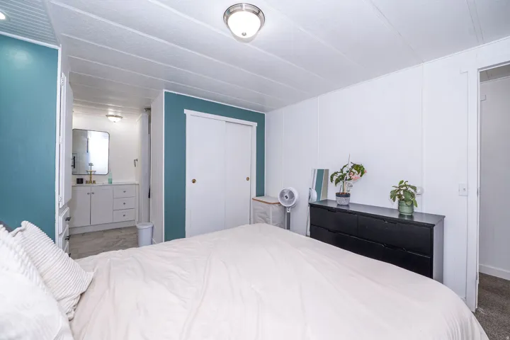 Bedroom featuring a full-height accent wall, white paneled walls, and a recessed sliding closet