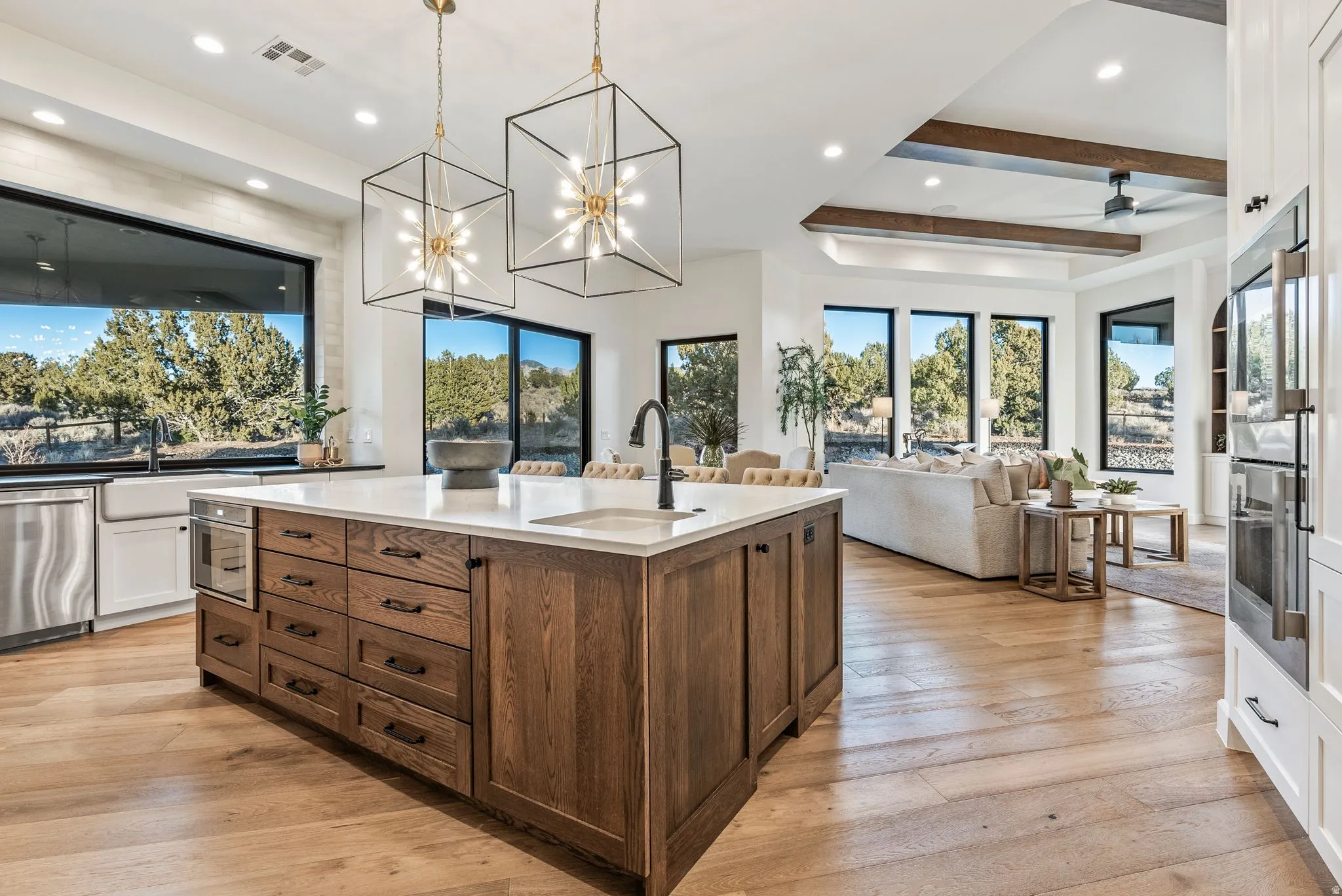 Gourmet kitchen featuring a large wood-finish island with integrated microwave, white countertops, a deep farmhouse sink, and stainless steel appliances