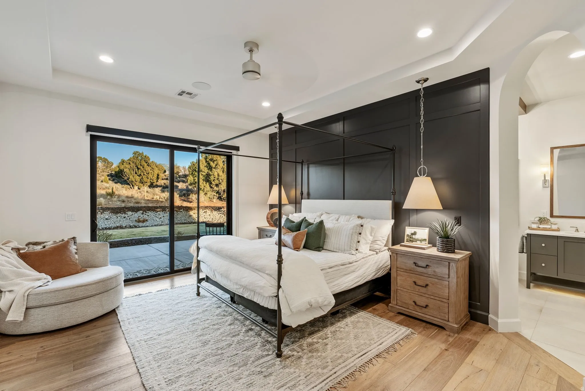 Bedroom featuring wood-finish flooring, a tray ceiling with recessed lighting, and a dark accent wall with paneling